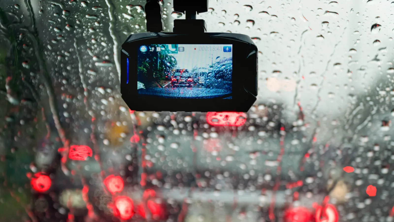 Camera hành trình đang ghi hình được gắn trên kính chắn gió ô tô trong điều kiện mưa.