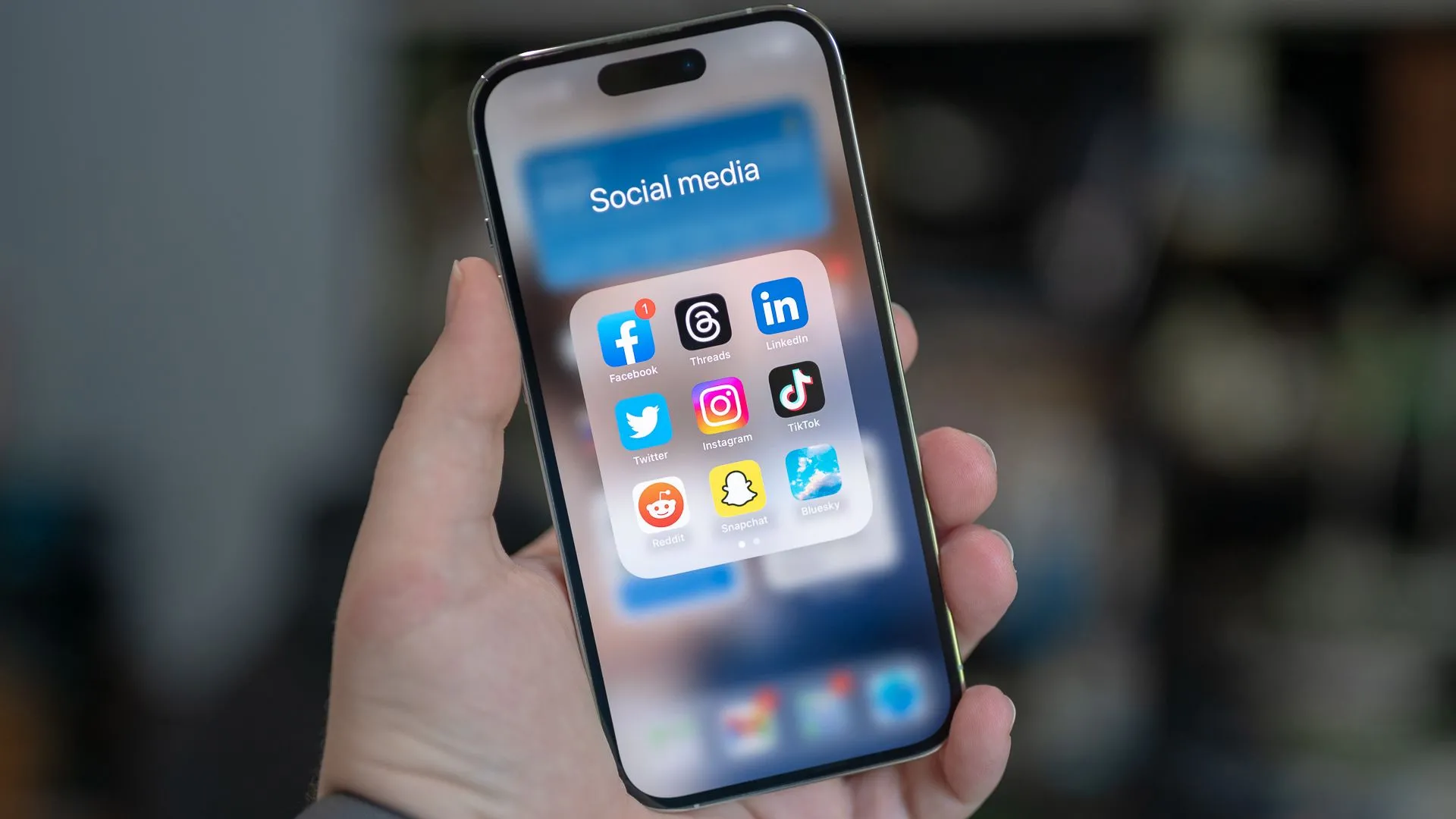 Điện thoại iPhone 14 Pro hiển thị thư mục ứng dụng mạng xã hội của Gen Z bao gồm Facebook, Threads, LinkedIn, Twitter, Instagram, TikTok, Reddit, Snapchat và Bluesky.