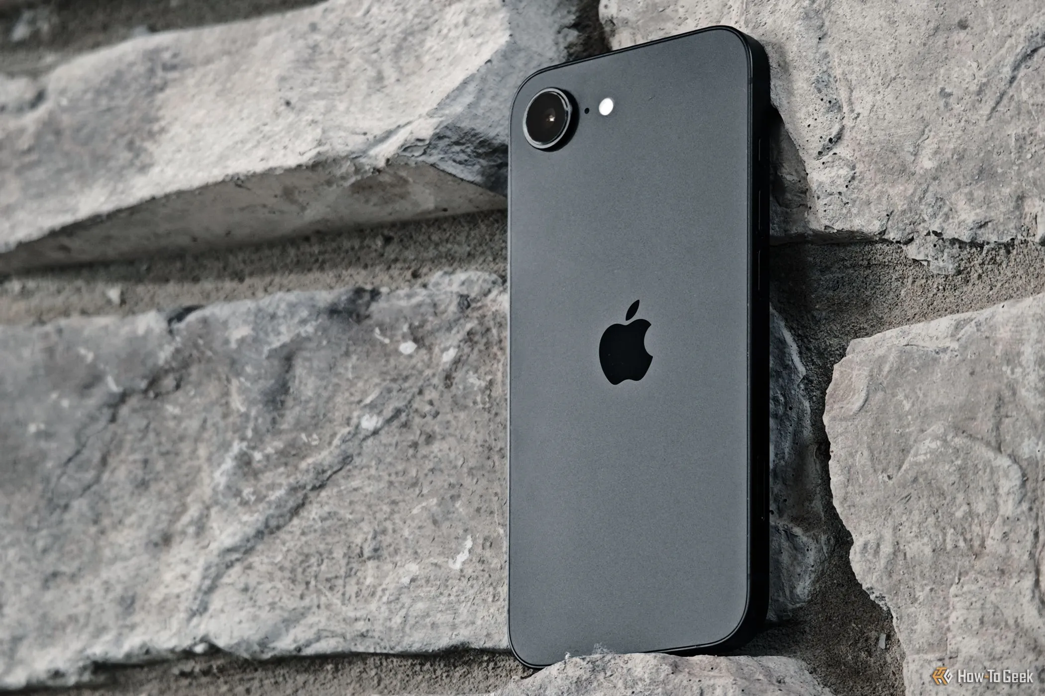 Điện thoại iPhone 16e tựa vào bức tường gạch