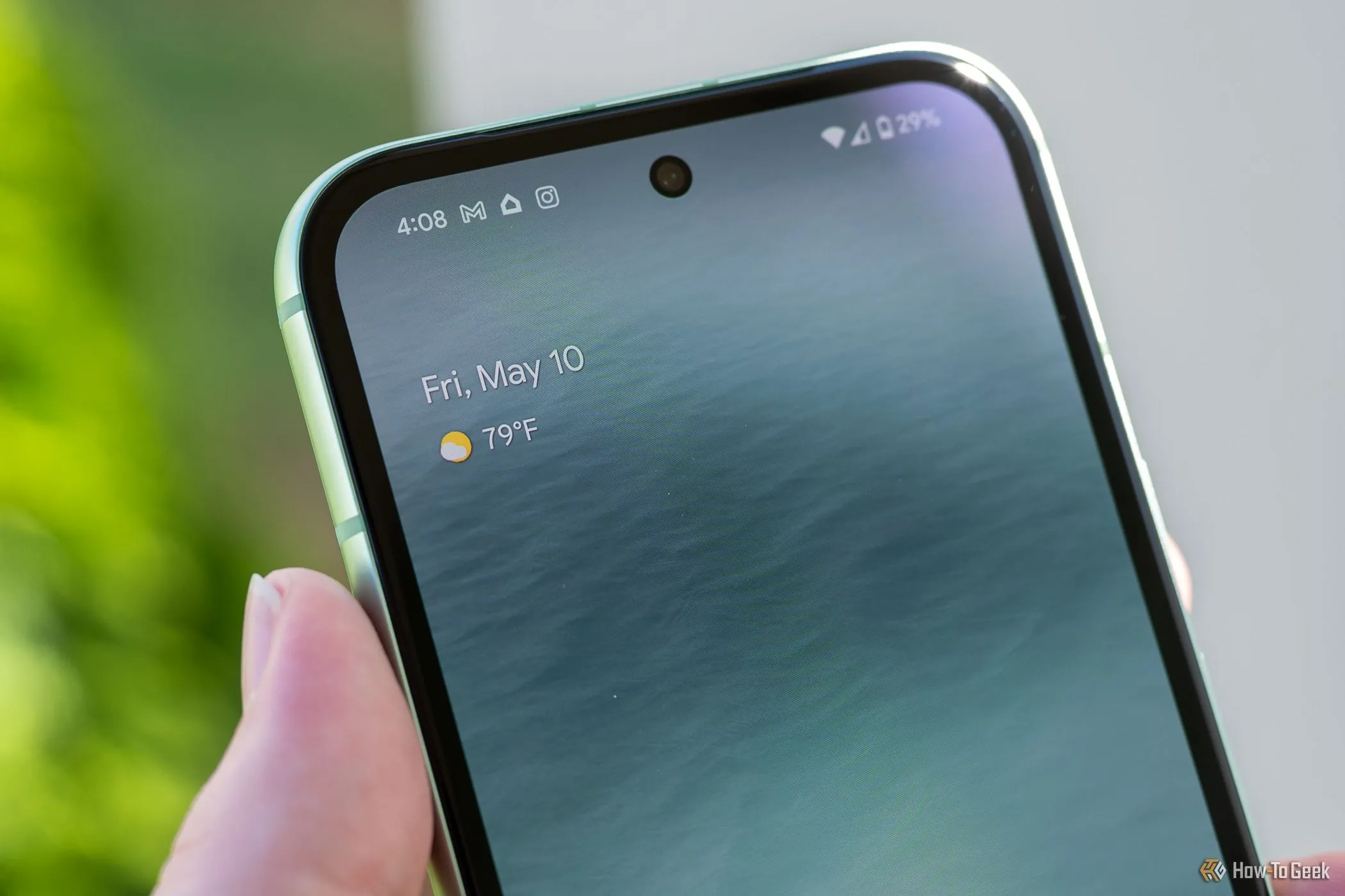 Điện thoại Pixel 8a được cầm trên tay, hiển thị camera trước dạng đục lỗ, cùng các biểu tượng kết nối Wi-Fi và 5G.