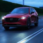 Hình ảnh Mazda CX-5 2025 màu đỏ di chuyển trong đô thị buổi tối, minh họa thiết kế ngoại thất.