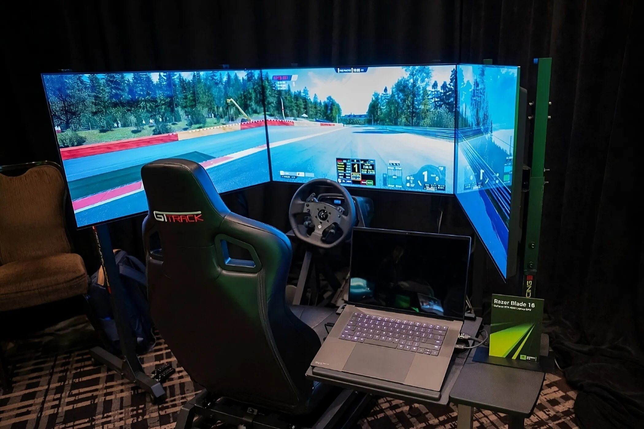 Máy tính xách tay Razer Blade 16 với GPU GeForce RTX 4080 hiển thị giao diện game đua xe mô phỏng, kèm theo vô lăng và bàn đạp chuyên dụng.