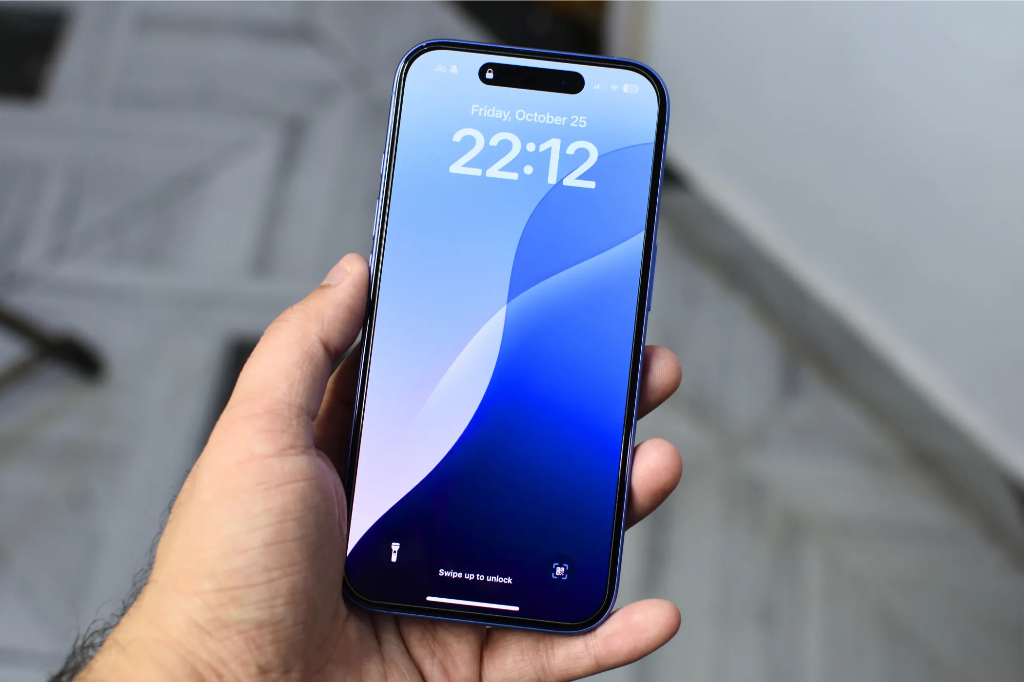 Người dùng cầm điện thoại iPhone 16 hiển thị hình nền màu xanh, tượng trưng cho trải nghiệm sử dụng smartphone