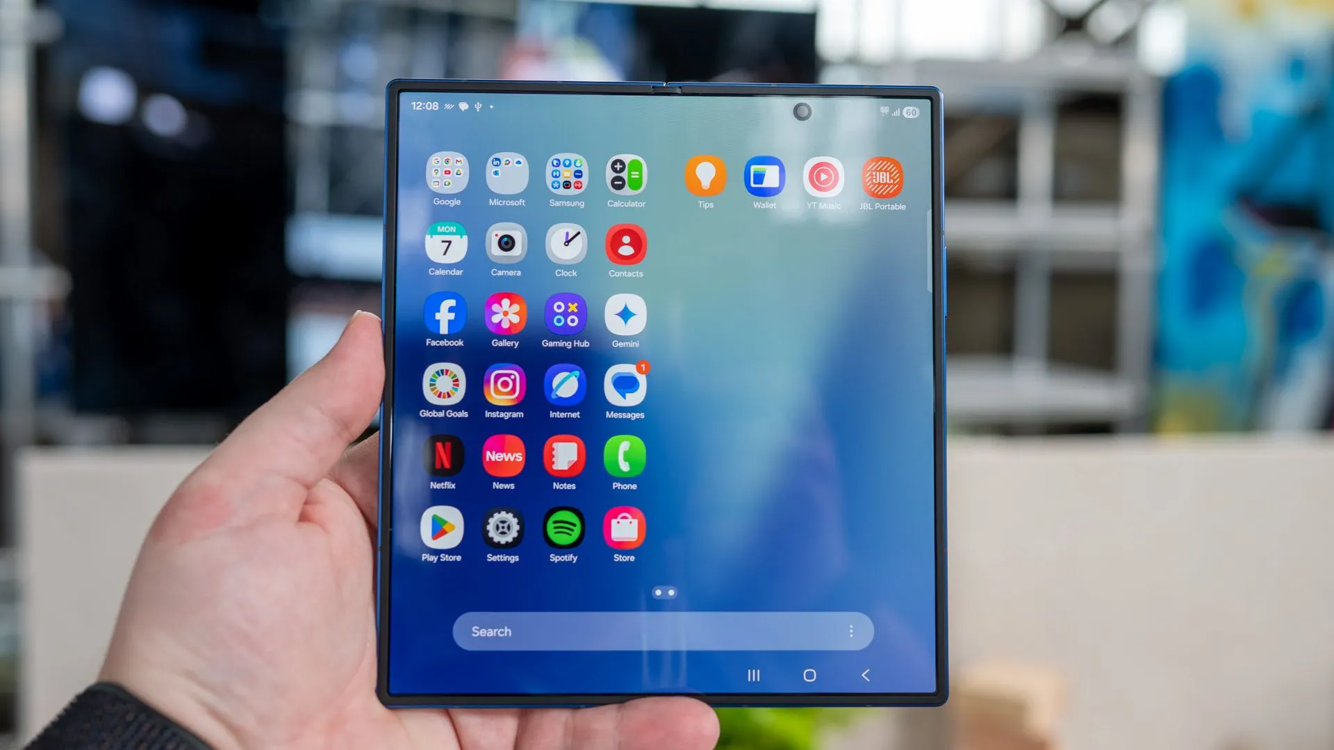 Người dùng cầm Galaxy Z Fold 7 đang mở, hiển thị ngăn kéo ứng dụng trên màn hình chính với vết cắt camera selfie rõ ràng