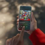 Người dùng cầm iPhone hiển thị ứng dụng Nintendo Music đang phát nhạc Jump Up, Super Star từ Super Mario Odyssey, biểu tượng sự tiện lợi và đa dạng nhạc game Nintendo trên di động.