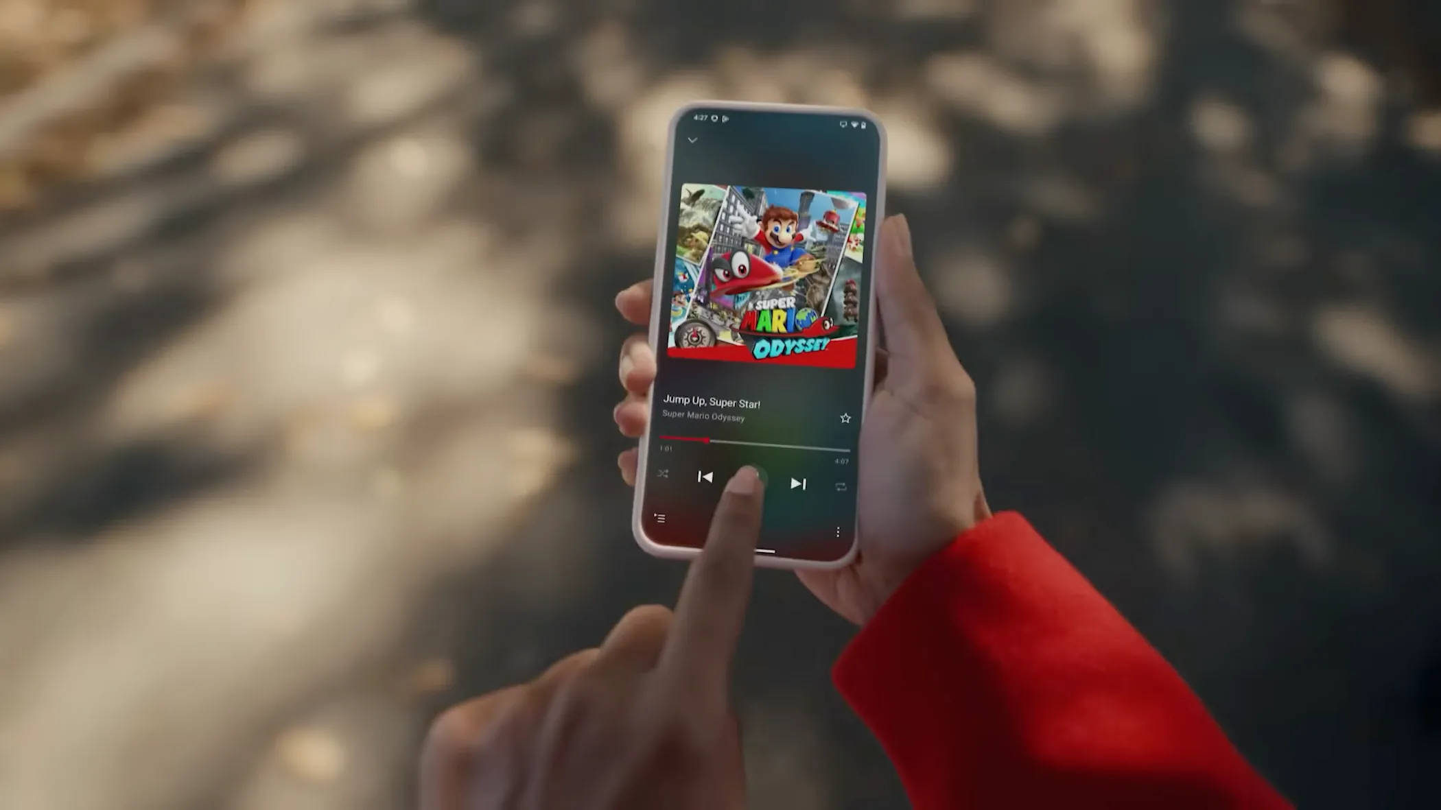 Người dùng cầm iPhone hiển thị ứng dụng Nintendo Music đang phát nhạc Jump Up, Super Star từ Super Mario Odyssey, biểu tượng sự tiện lợi và đa dạng nhạc game Nintendo trên di động.
