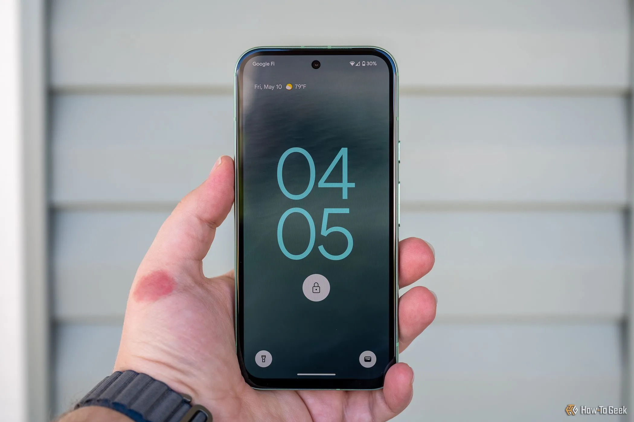 Người dùng đang cầm điện thoại Google Pixel 8a, hiển thị màn hình khóa, minh họa khả năng hỗ trợ phần mềm lâu dài.