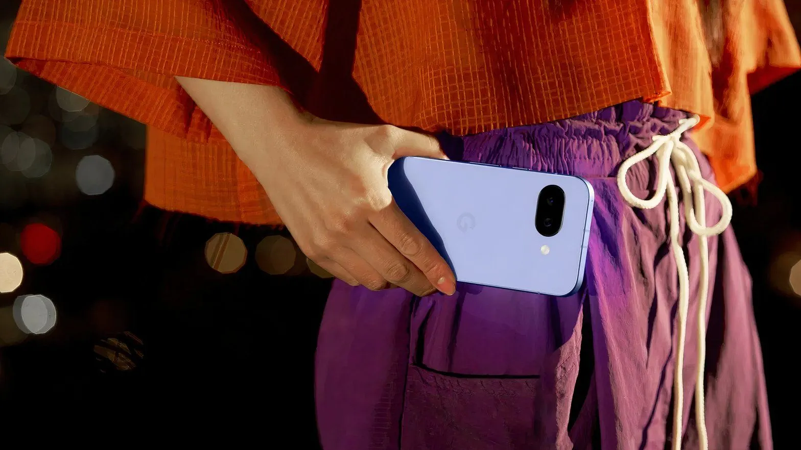 Người phụ nữ đang cầm điện thoại Google Pixel 9a ở ngang eo