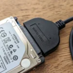 Ổ cứng di động kết nối với adapter USB trên bề mặt gỗ.