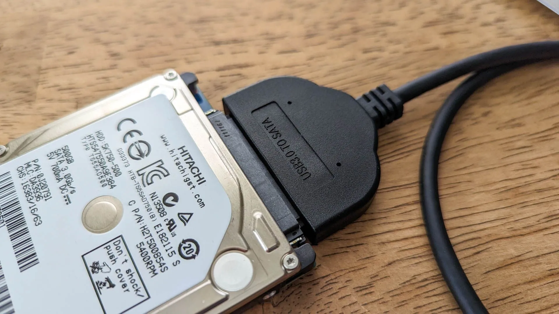 Ổ cứng di động kết nối với adapter USB trên bề mặt gỗ.