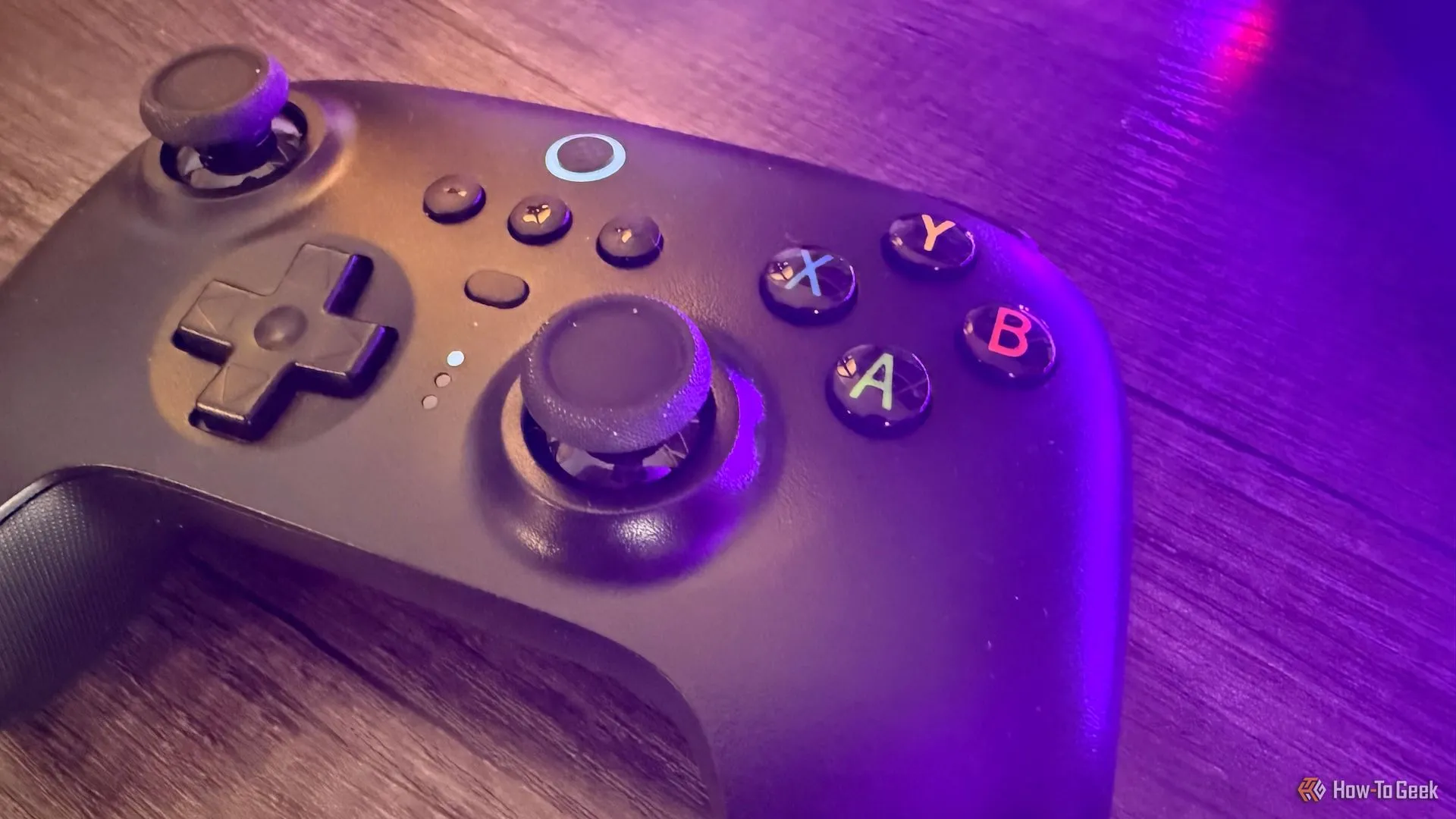 Tay cầm chơi game 8BitDo Ultimate 2.4G màu tím nằm trên bàn với ánh sáng màu tím mờ ảo.