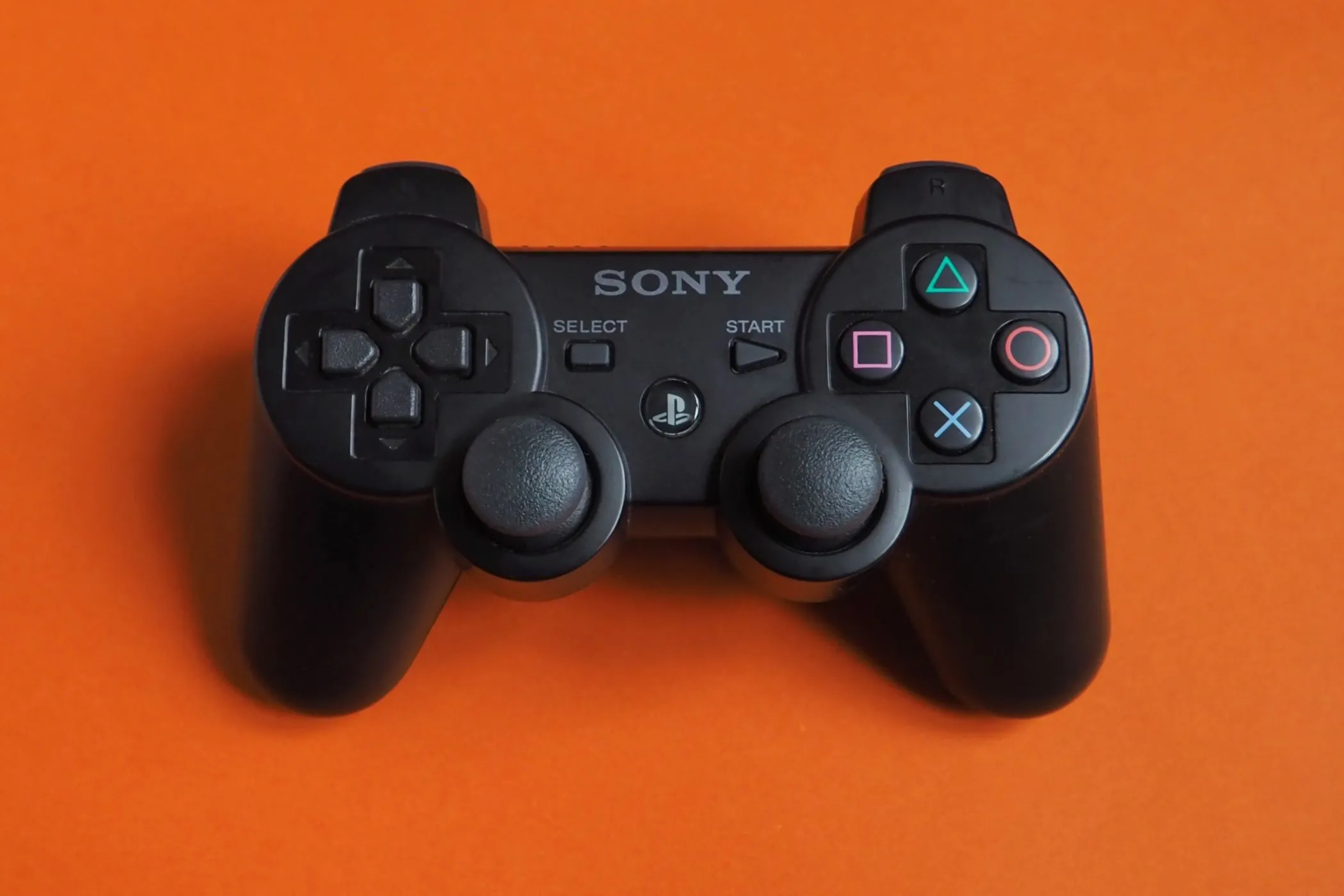 Tay cầm Sony PlayStation 2 DualShock được đặt trên bề mặt màu xanh