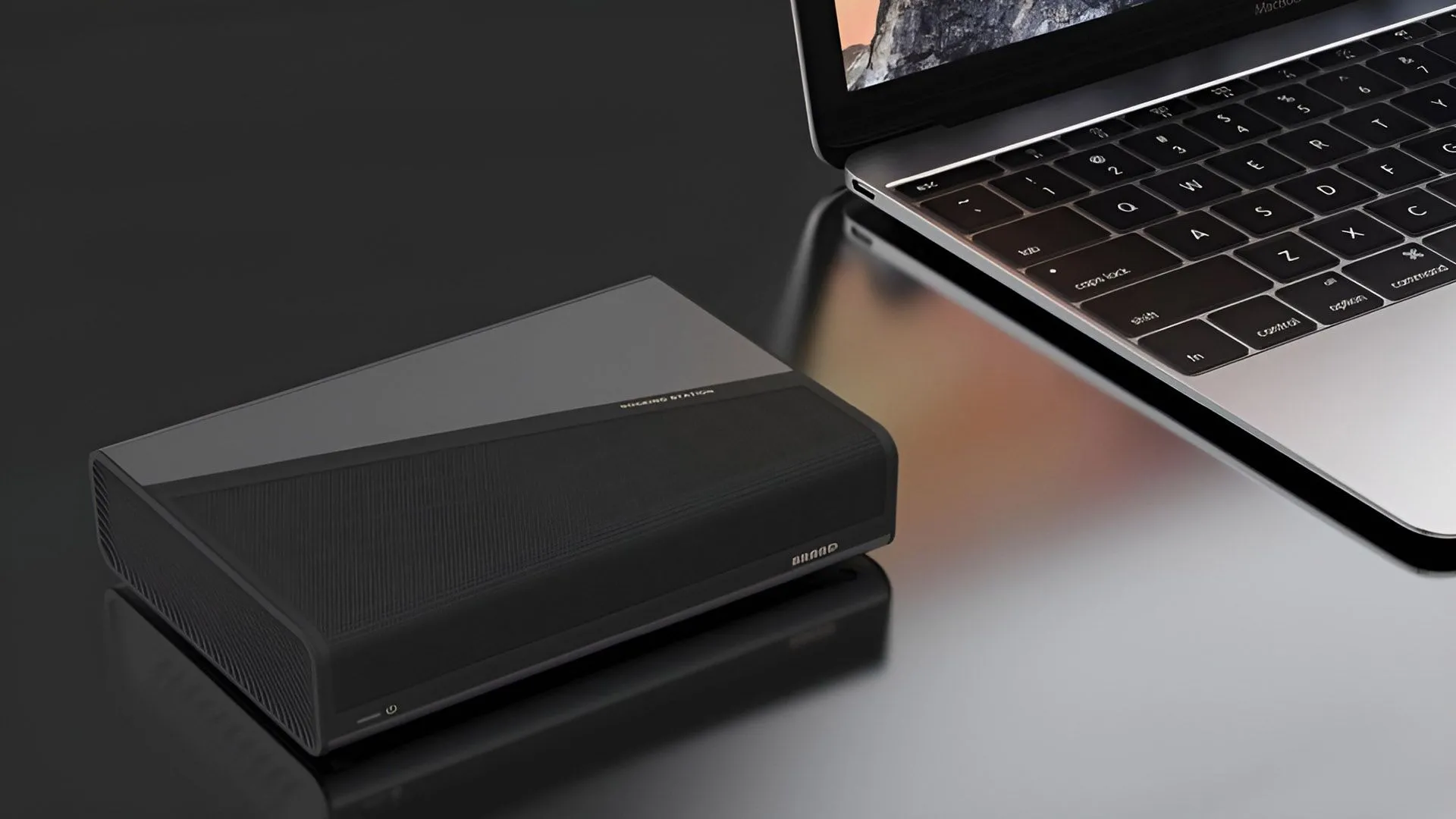 Thiết bị card đồ họa rời GMK AD-GP1 siêu nhỏ gọn màu xám bạc, đặt cạnh một chiếc laptop để minh họa kích thước
