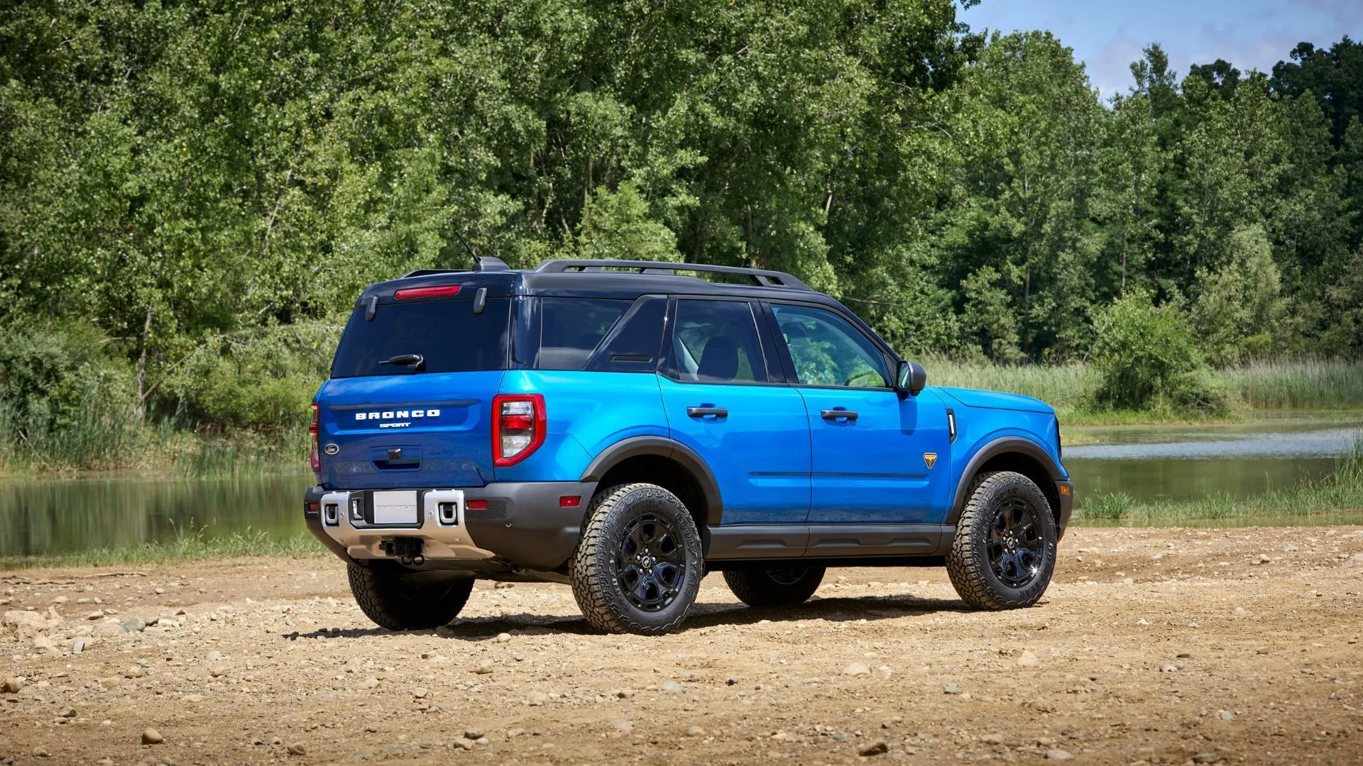 Xe Ford Bronco Sport 2025 màu xanh đậu trên đường sỏi với cây cối phía sau, minh họa lỗi khóa trẻ em trên Bronco 4 cửa.