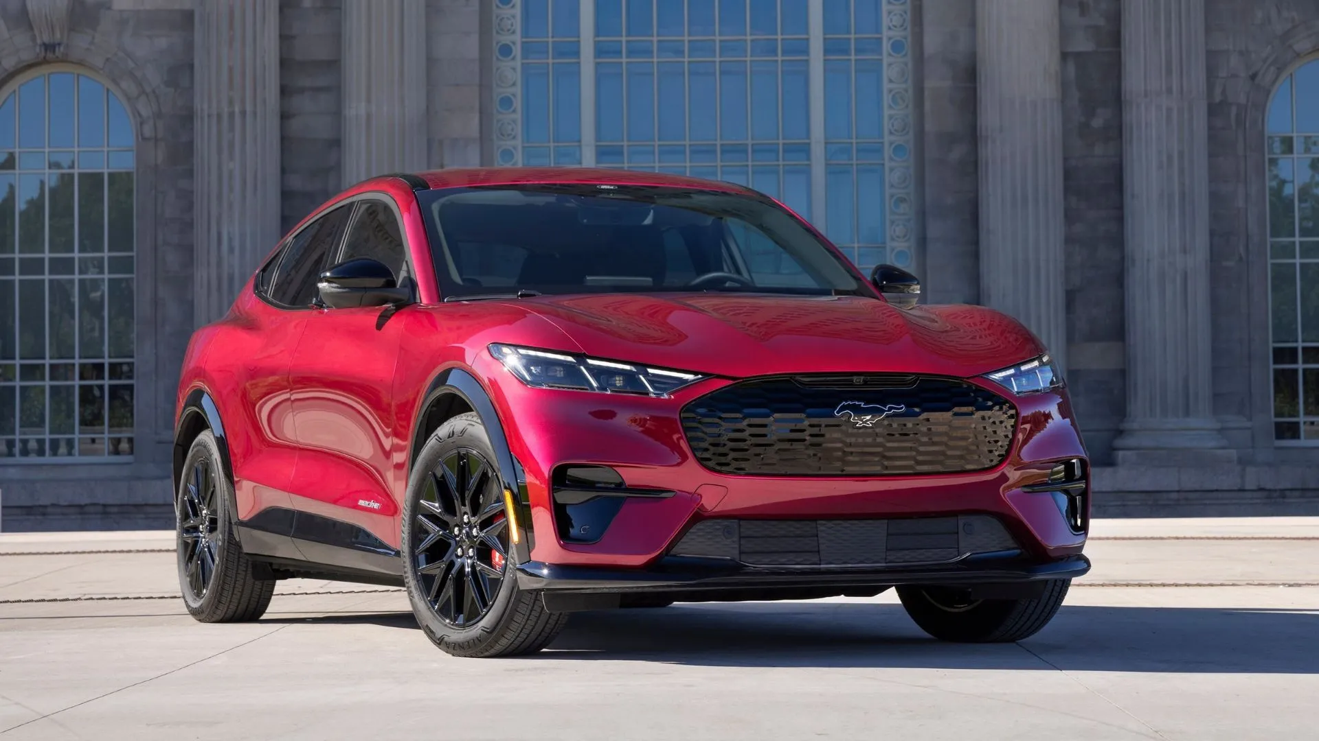 Xe Ford Mustang Mach-E 2025 màu đỏ với tòa nhà phía sau, biểu thị lỗi thanh khóa đỗ xe của hộp số.